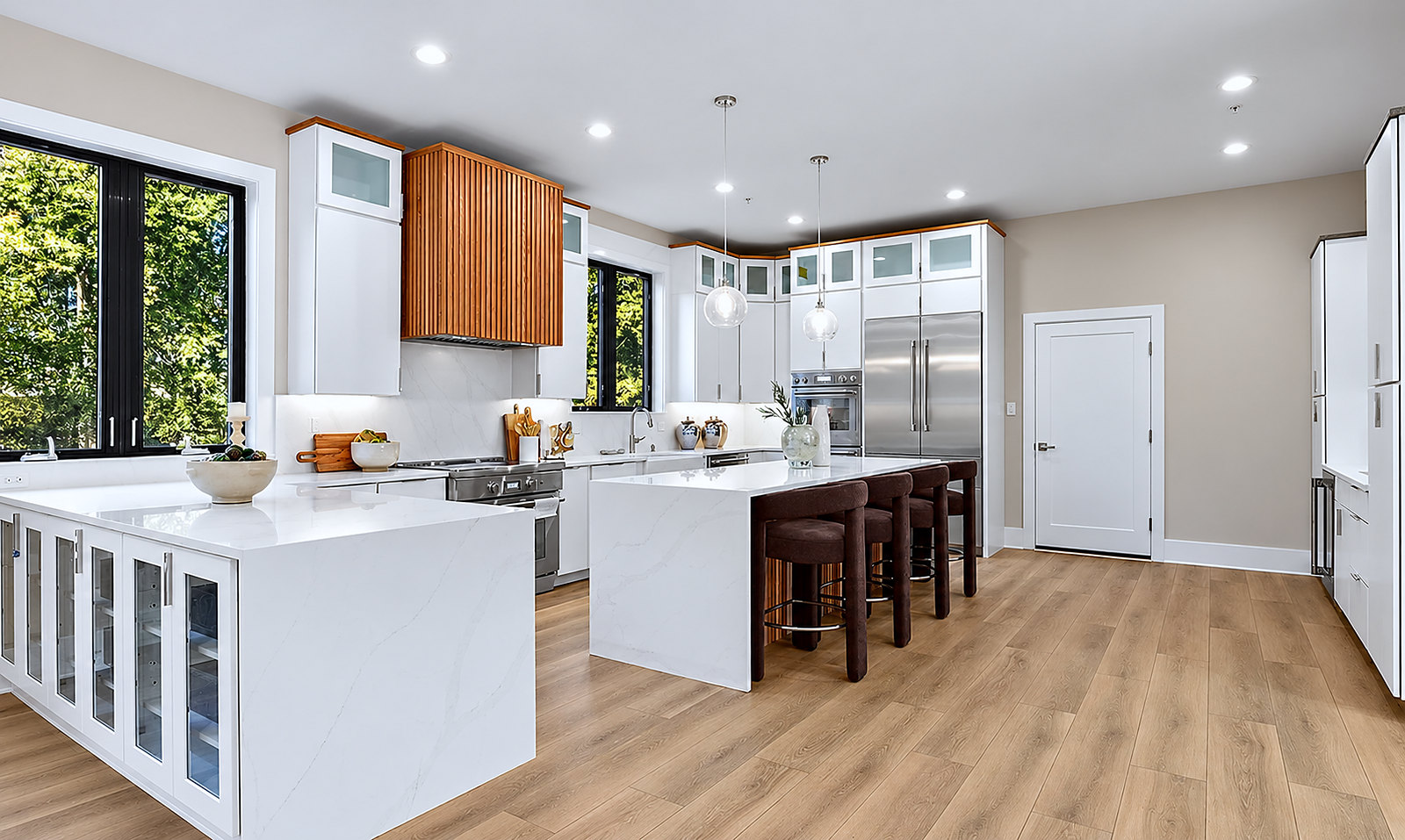 White kitchen with waterfall quartz island, wood slat range hood and glass globe pendants