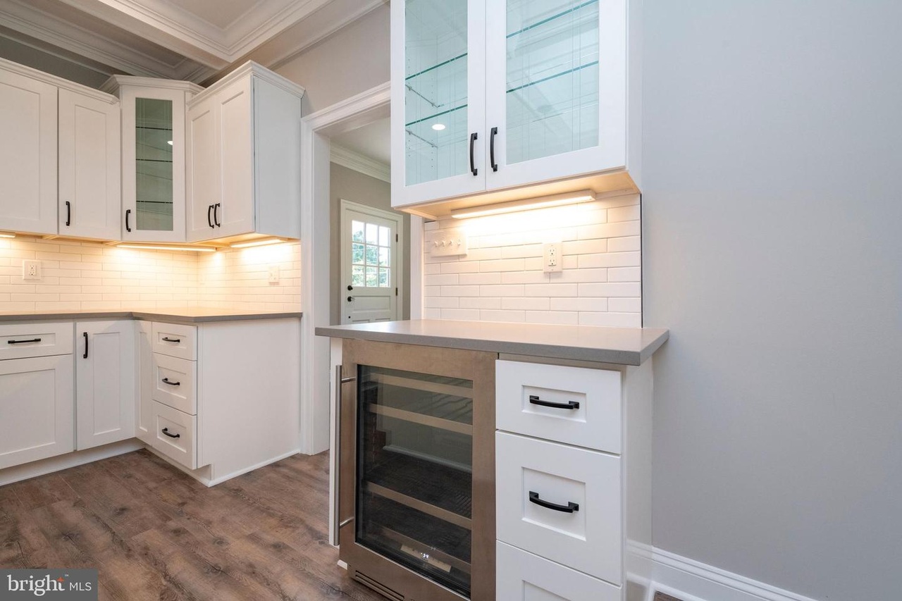 Chapel Ridge — kitchen cabinetry and beverage refrigerator beside tall windows