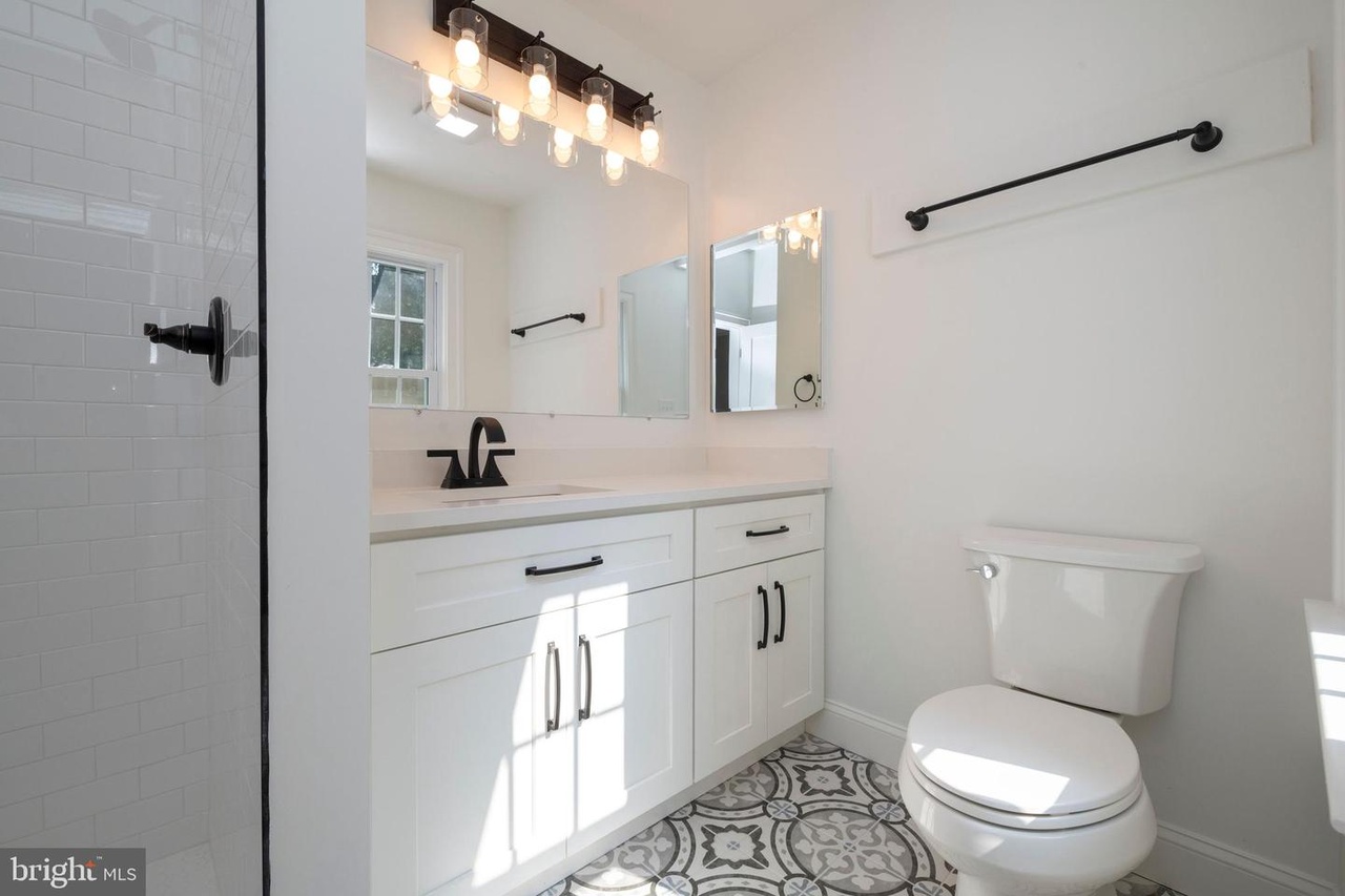 Chapel Ridge — bathroom with a white vanity, dark fixtures and patterned tile floor