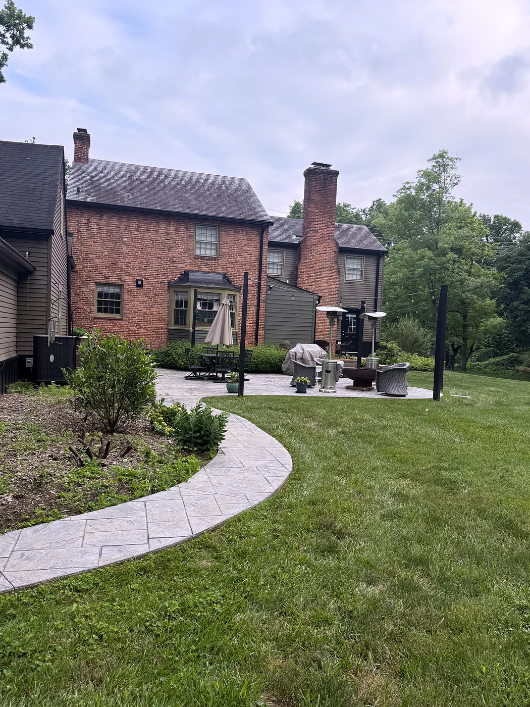 Stamped concrete walkway and patio beside a brick home