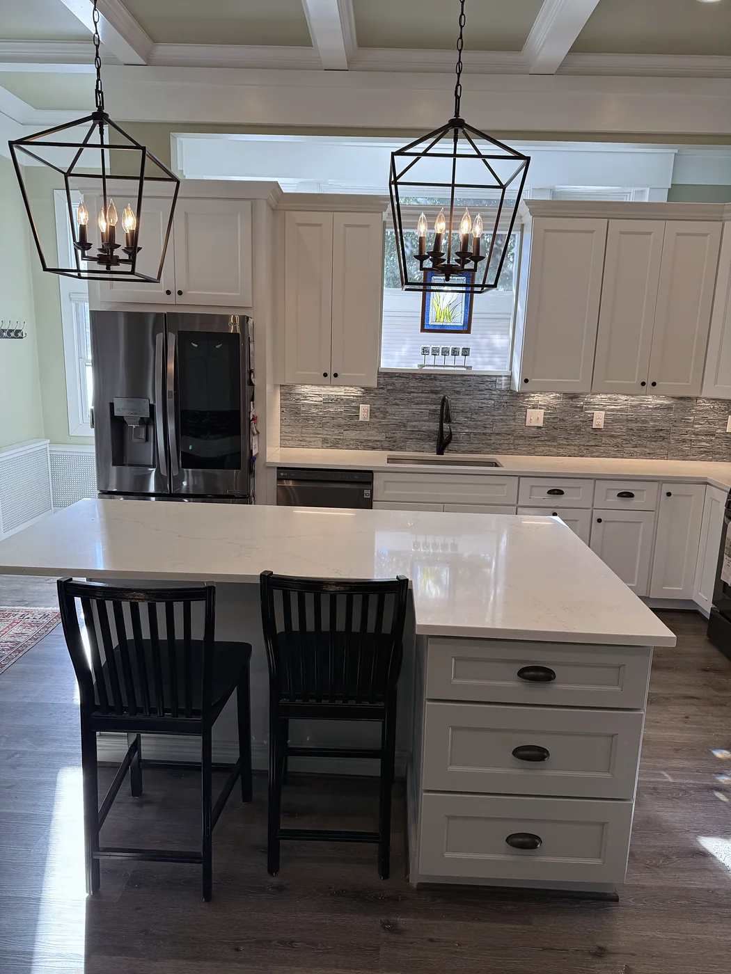 White kitchen with a quartz island, lantern pendants and tile backsplash
