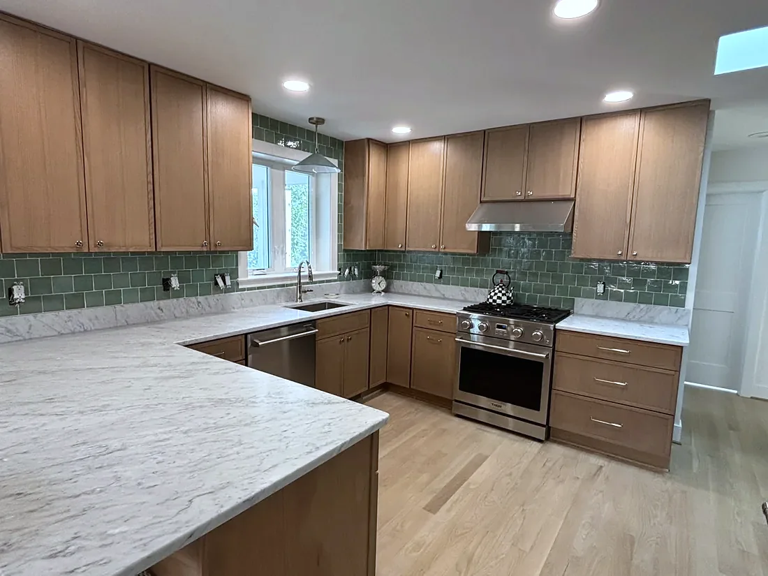 Walnut kitchen cabinets with a green glass tile backsplash